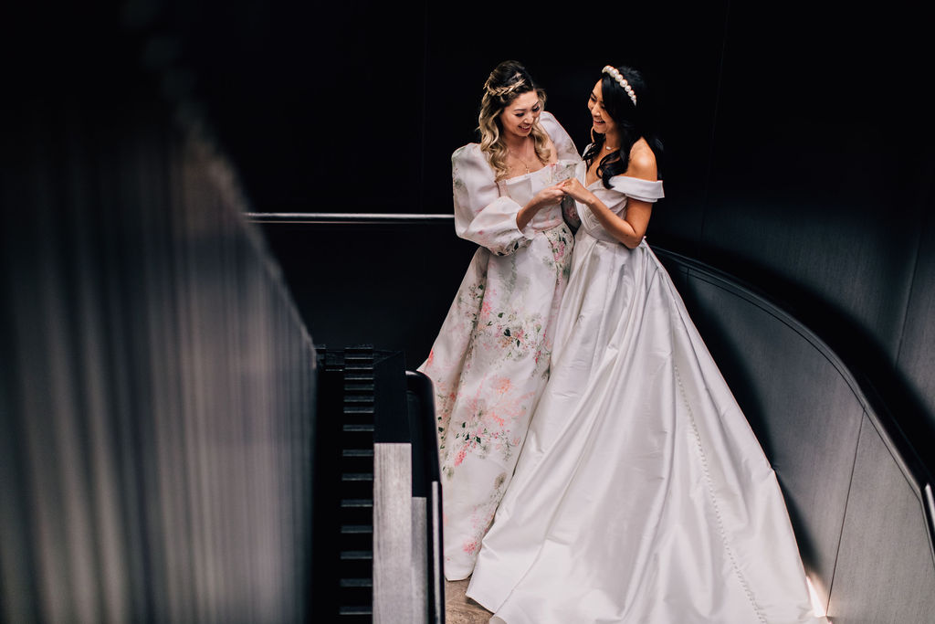 Two women, one in a floral dress and the other in a white wedding gown ...