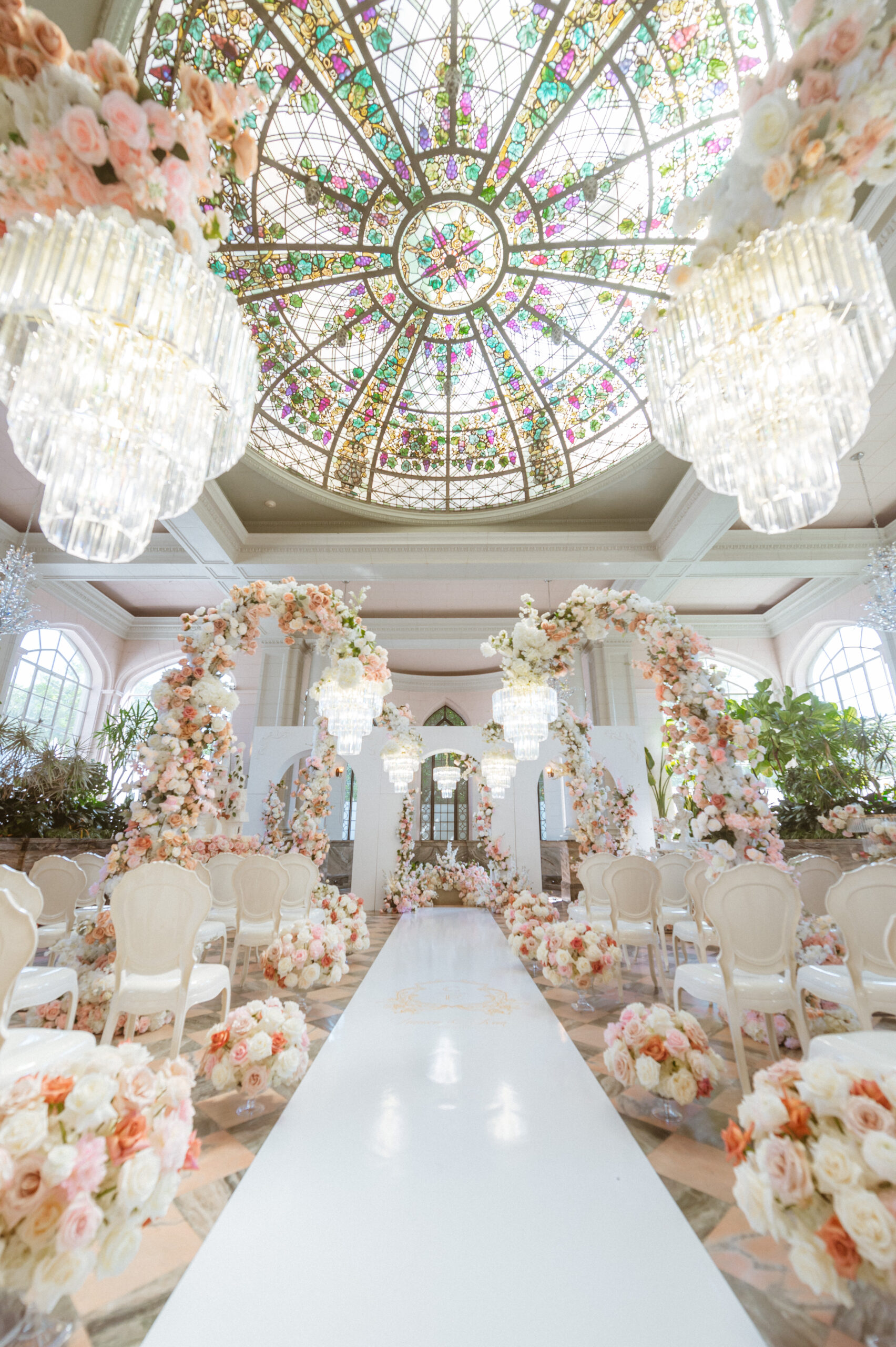 A lavish wedding venue reminiscent of a fairy-tale features a grand aisle  lined with pastel, image size:1704x2560