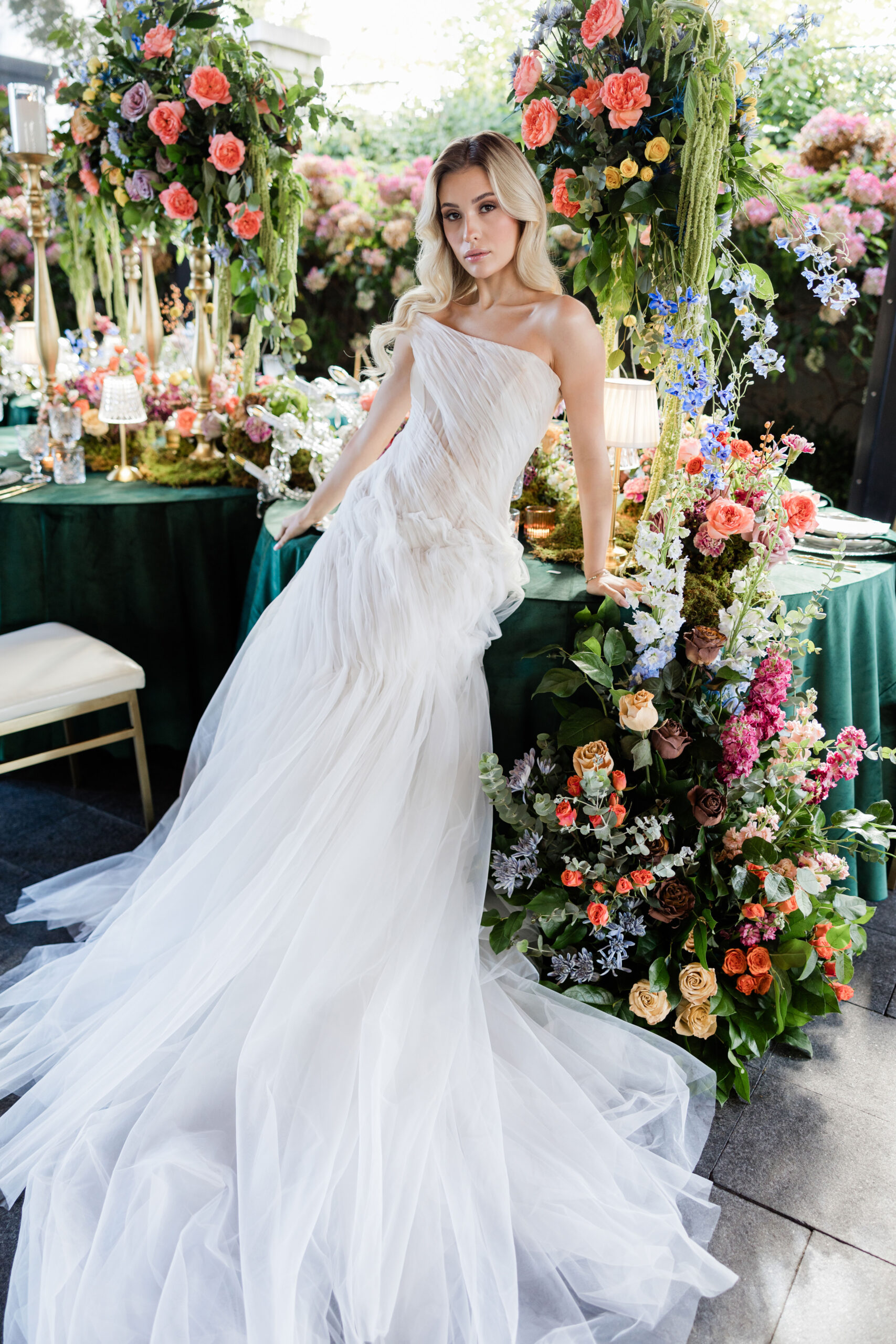 A woman in a flowing white gown stands near a table adorned with ...