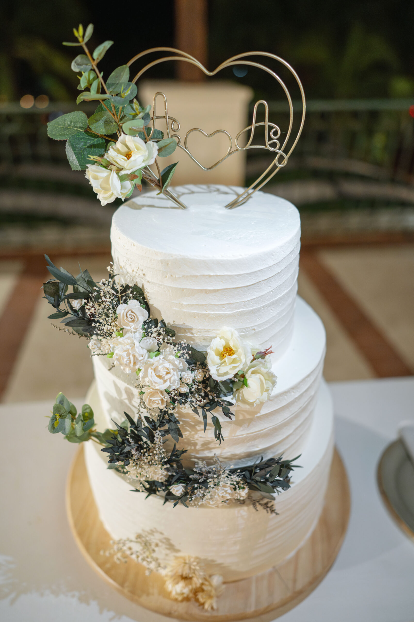 A three-tier white wedding cake decorated with white and cream