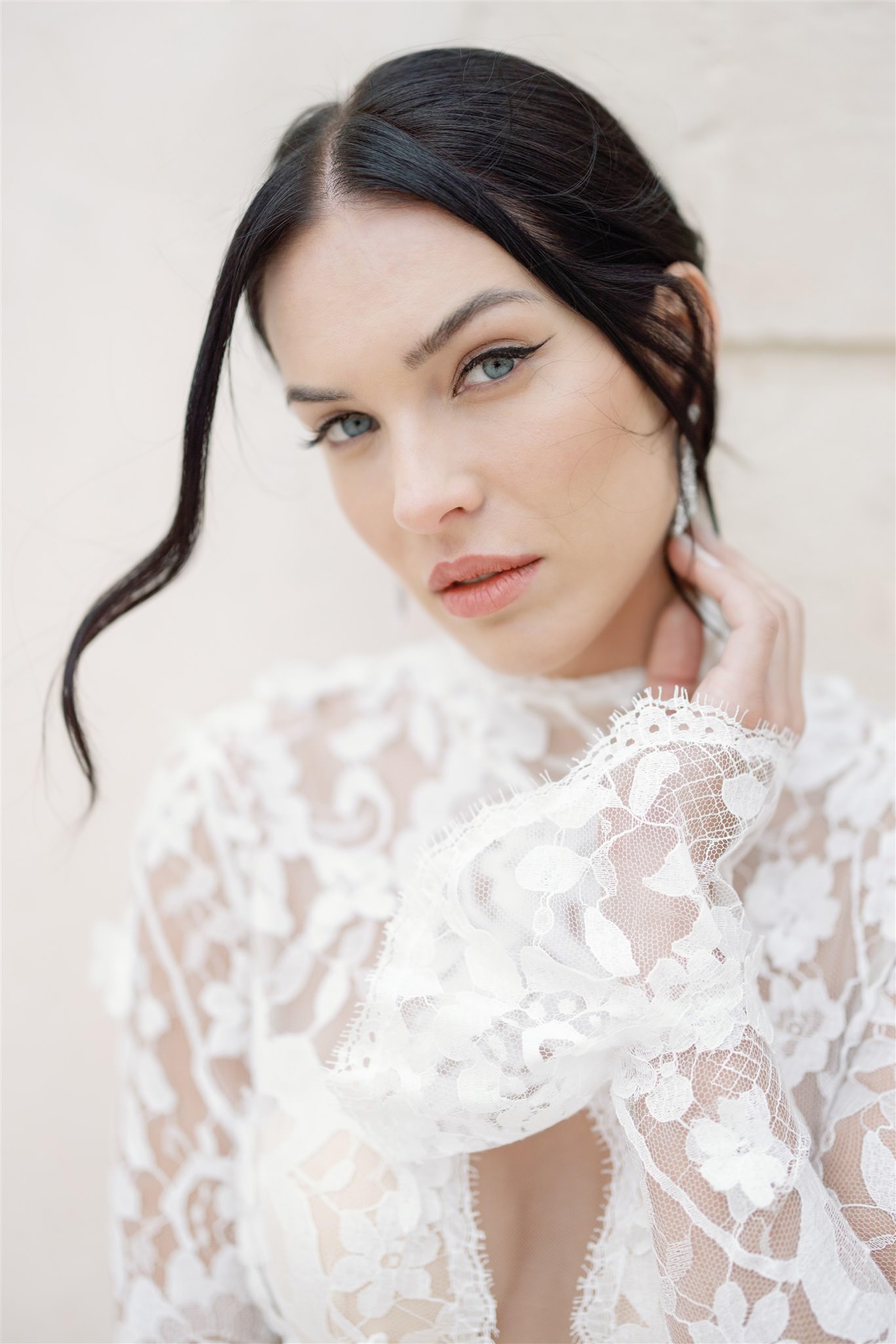 A woman with dark hair and light eyes wears a white lace top with ...