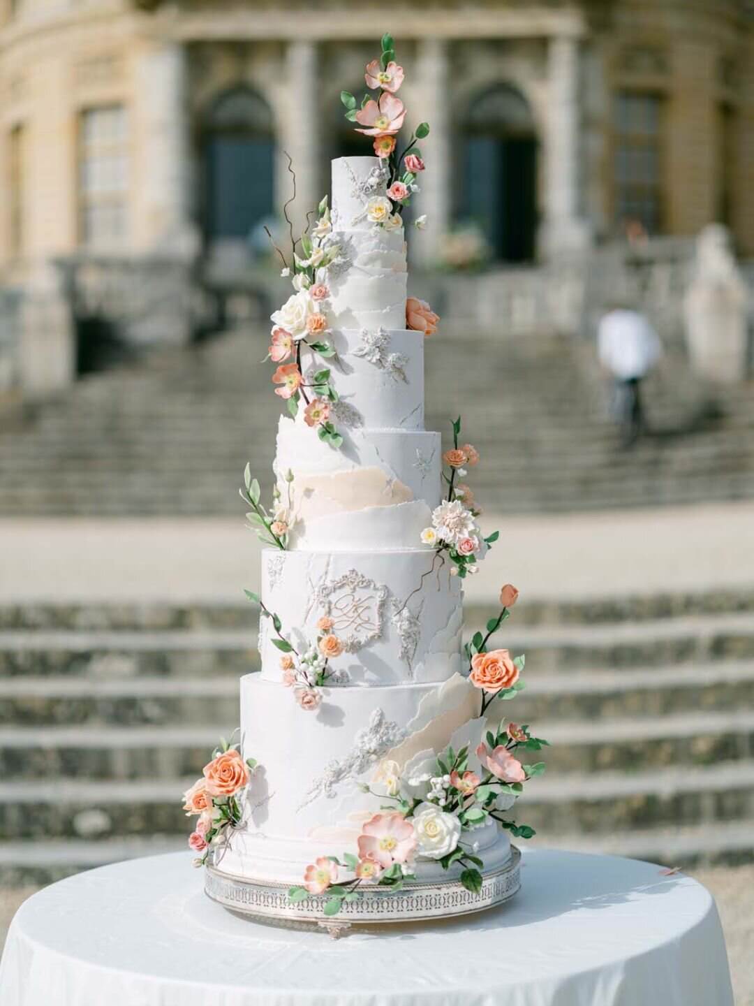 A tall, elegant white wedding cake with six tiers, decorated with delicate  pastel pink and peach, image size:1080x1440