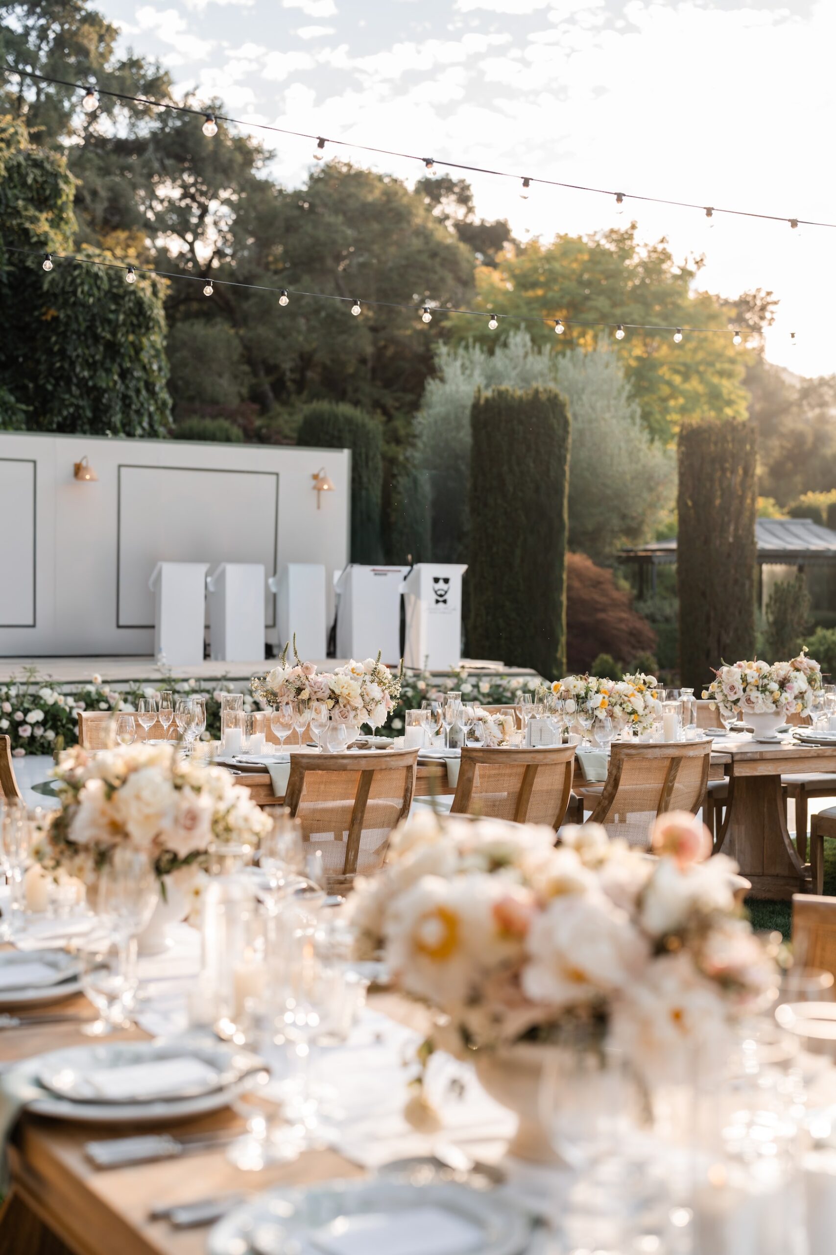 Elegant outdoor wedding reception setup with wooden tables, white ...