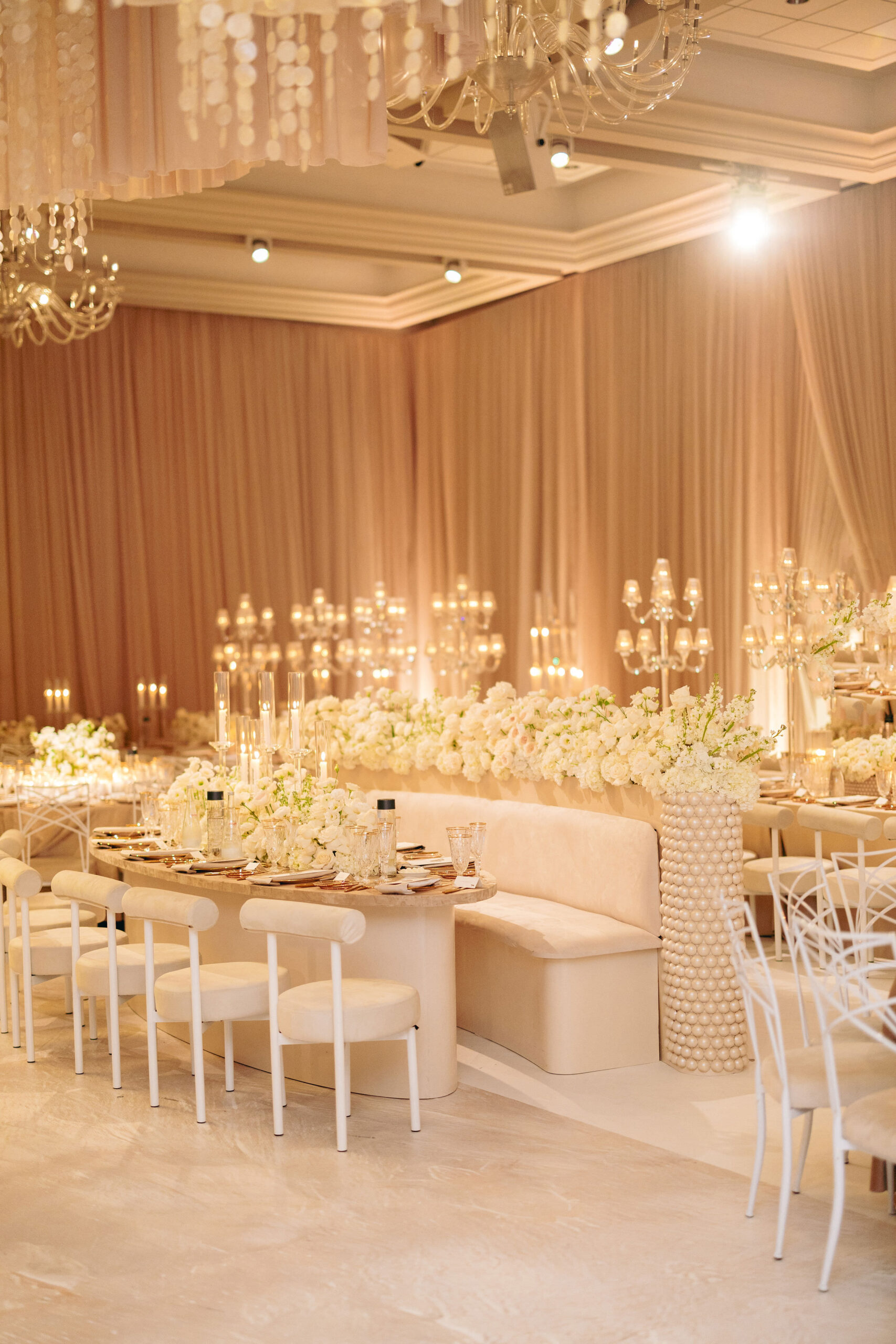 Elegant wedding reception hall with cream and gold decor, long banquet