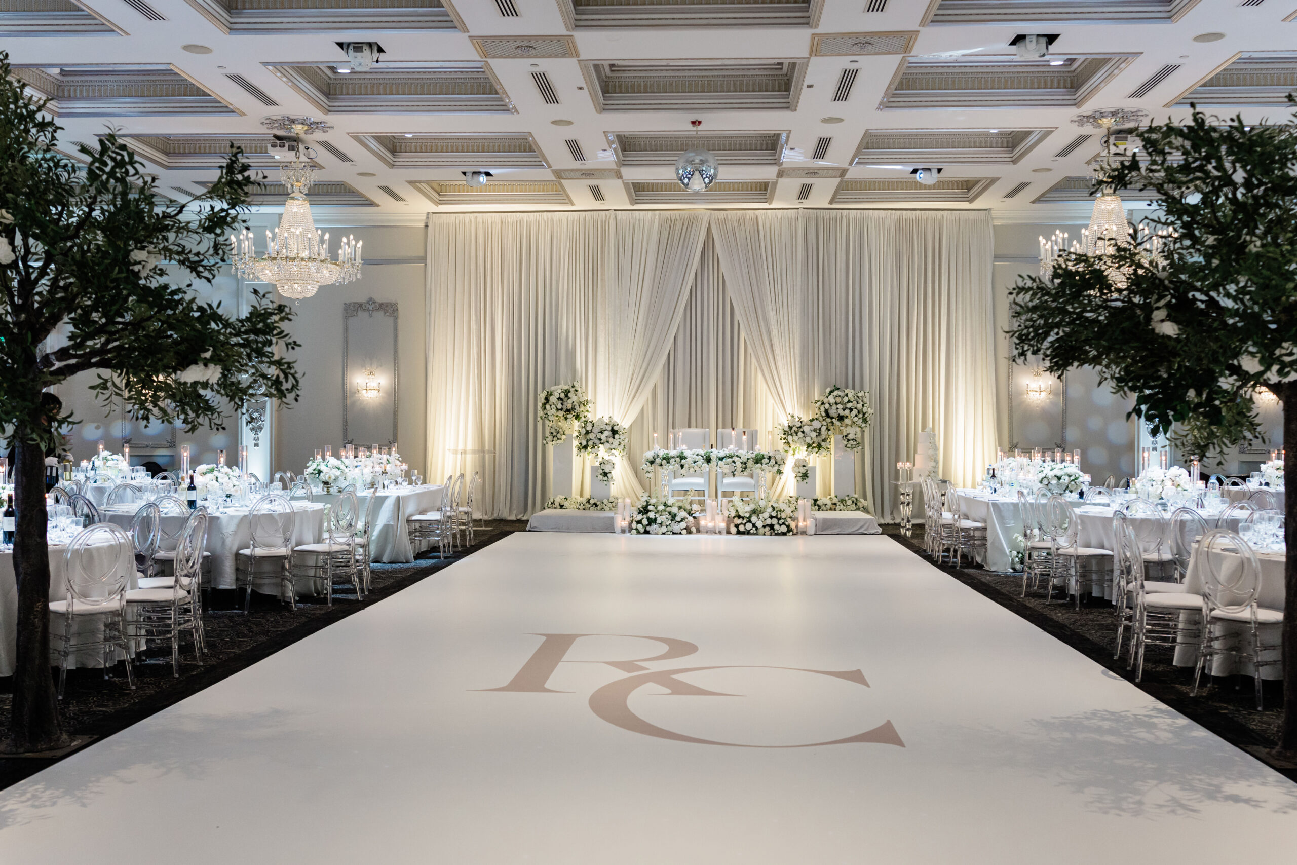 Elegant wedding reception hall with chandeliers, white draped backdrop ...