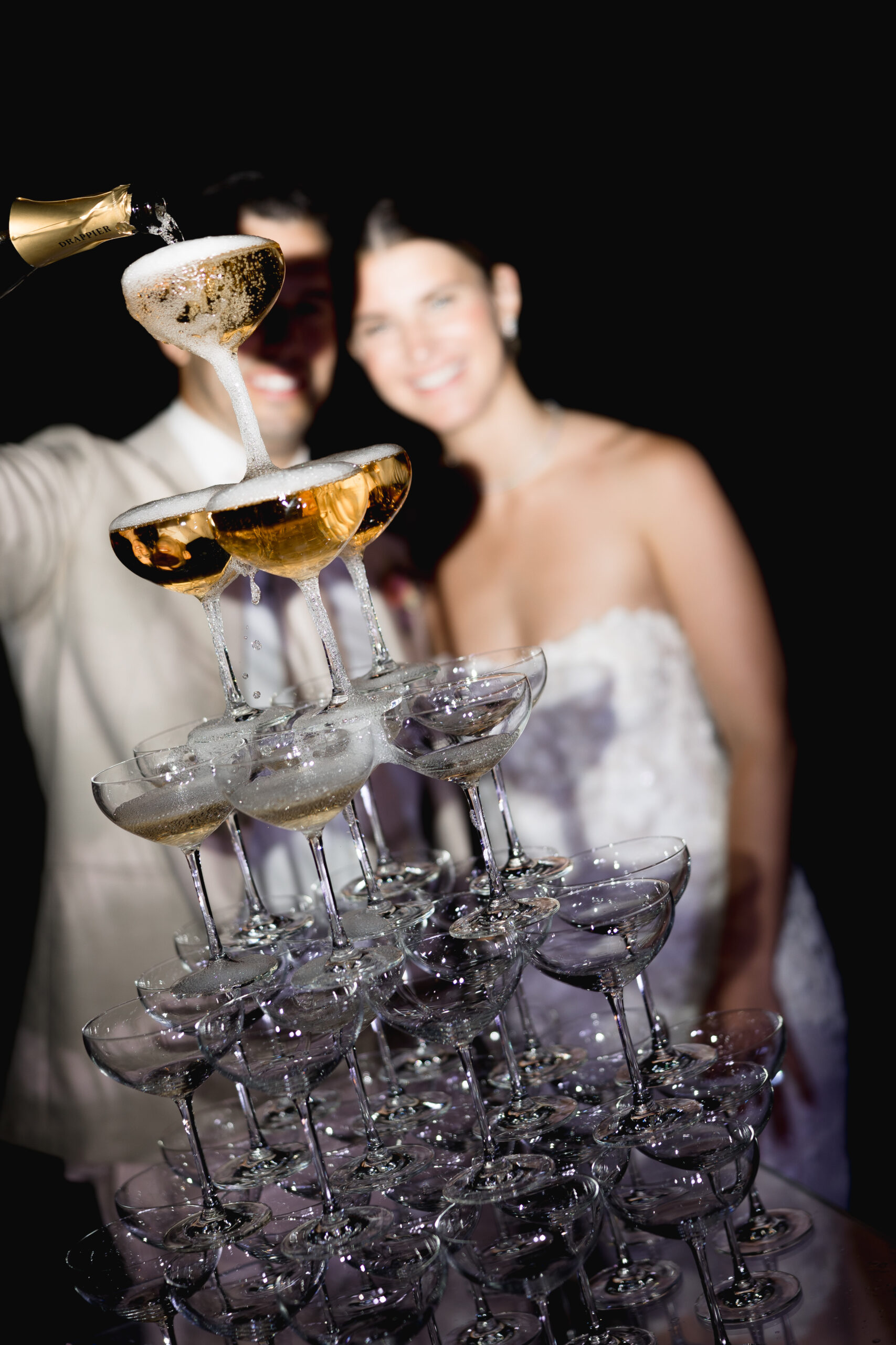 A person pours champagne into the top glass of a champagne tower at a Switzerland destination