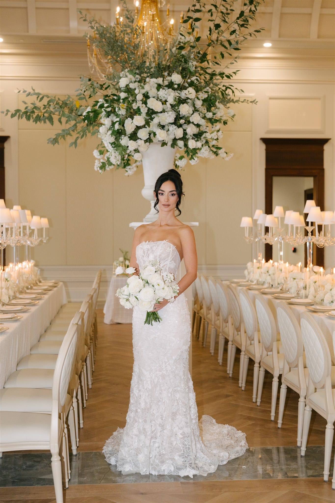 A bride in a white, off-the-shoulder lace gown holds a bouquet of white ...