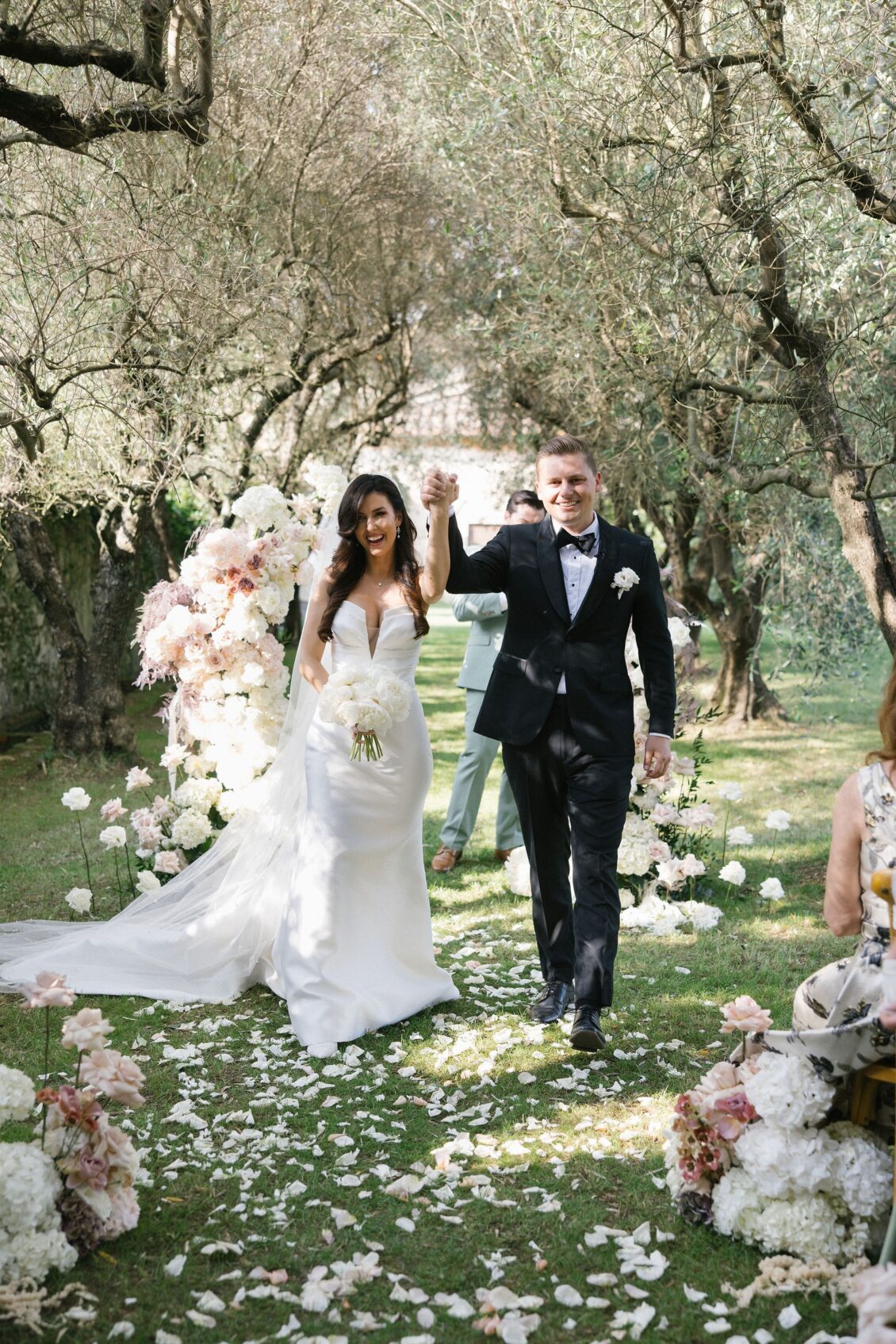 Newlyweds celebrating their recessional through the flower-lined aisle