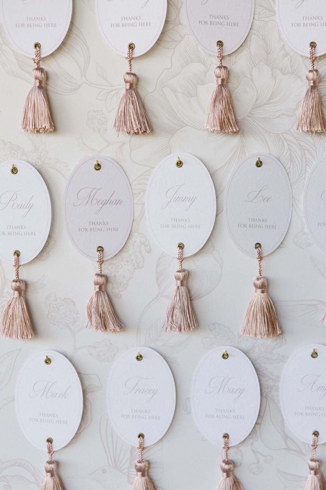 Tasselled escort cards with custom floral-pattern stationery