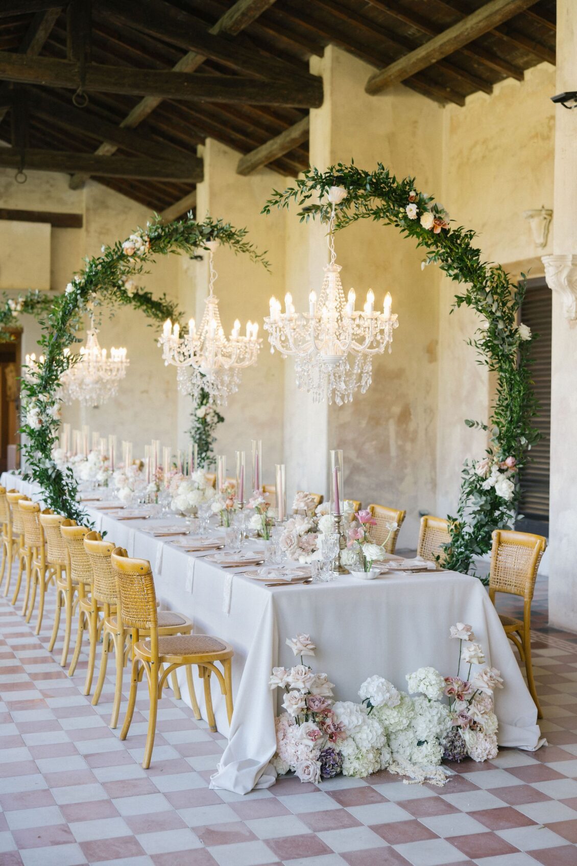 Blush and white reception table with greenery and crystal chandeliers