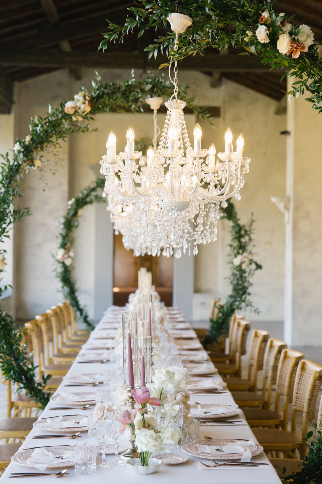 Crystal chandeliers above the long Tuscany wedding dinner table
