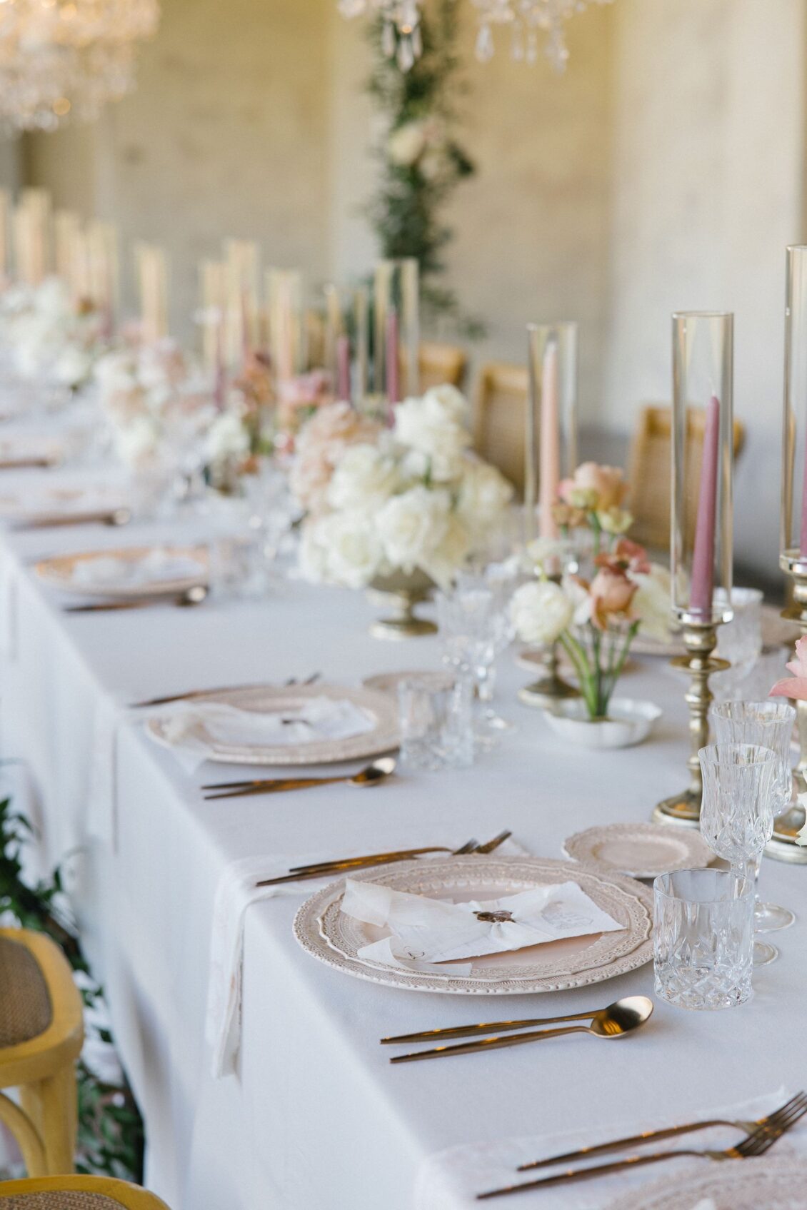 Blush taper candles and layered place settings on the reception table