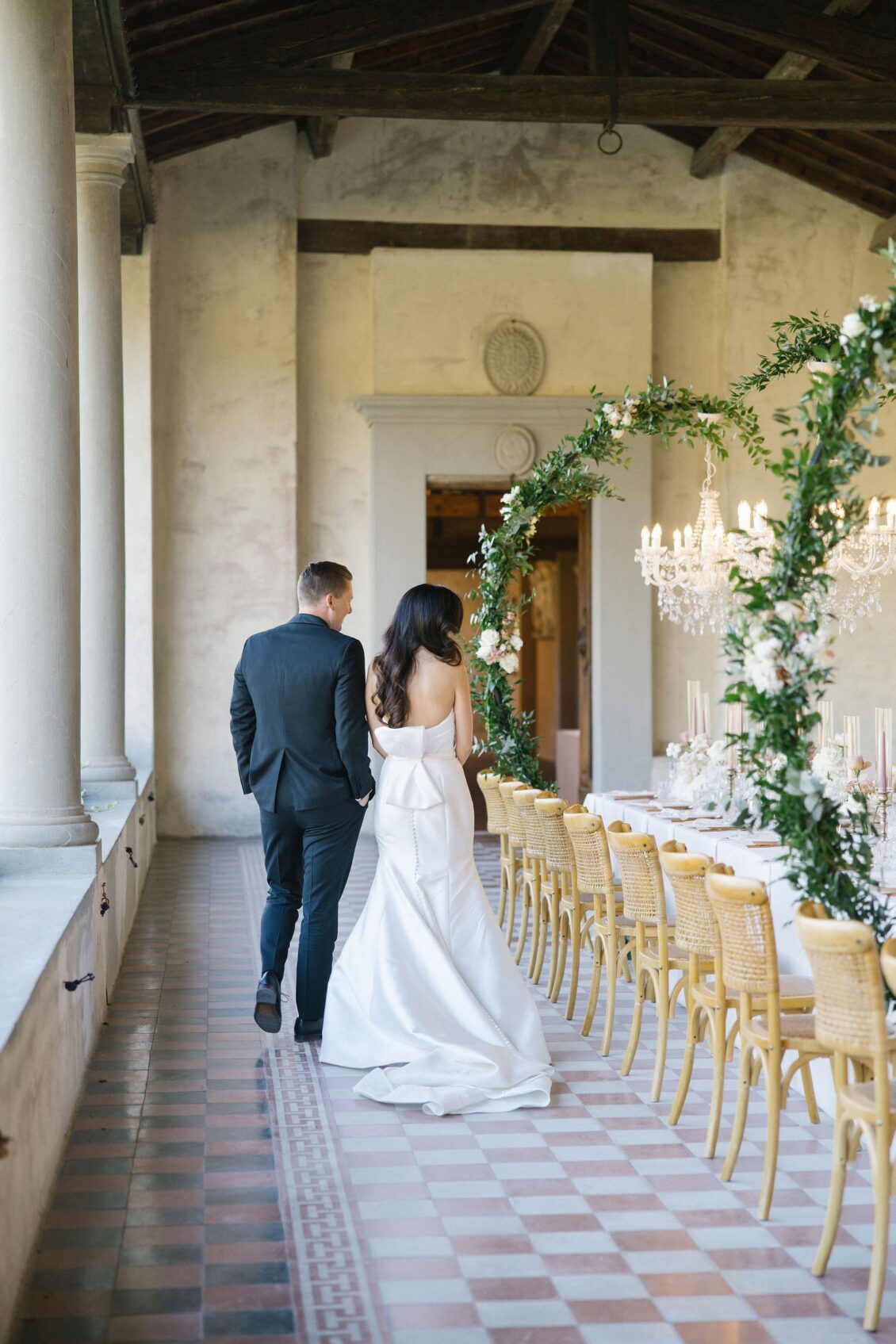 Jennifer and Travis walking beside their chandelier-lit dinner table