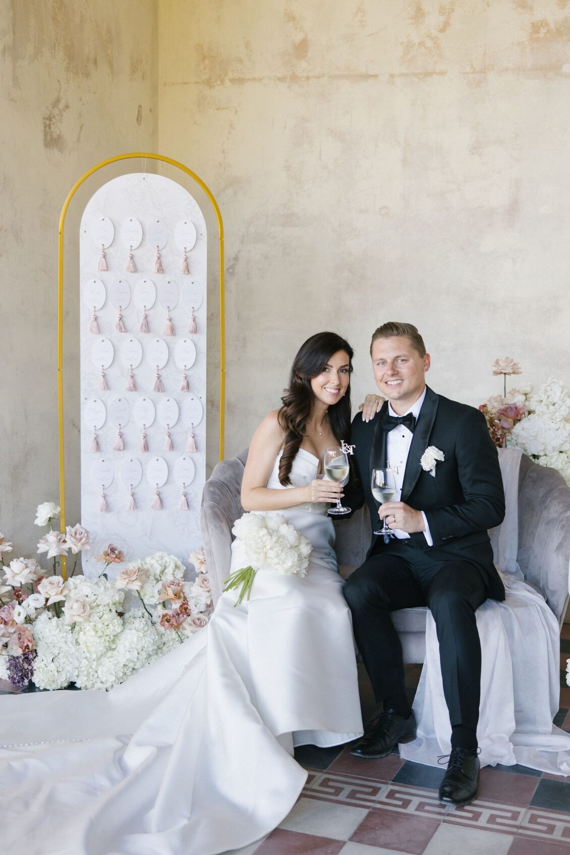 Jennifer and Travis seated in the blush floral escort-card lounge