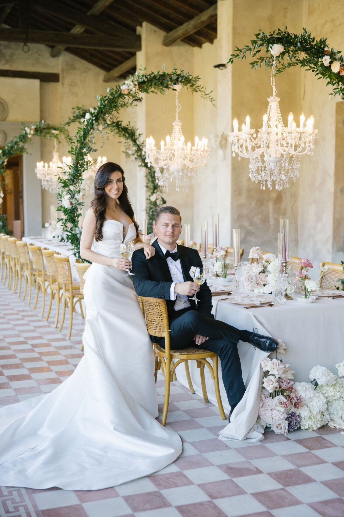 Jennifer and Travis beside the chandelier-lit reception table