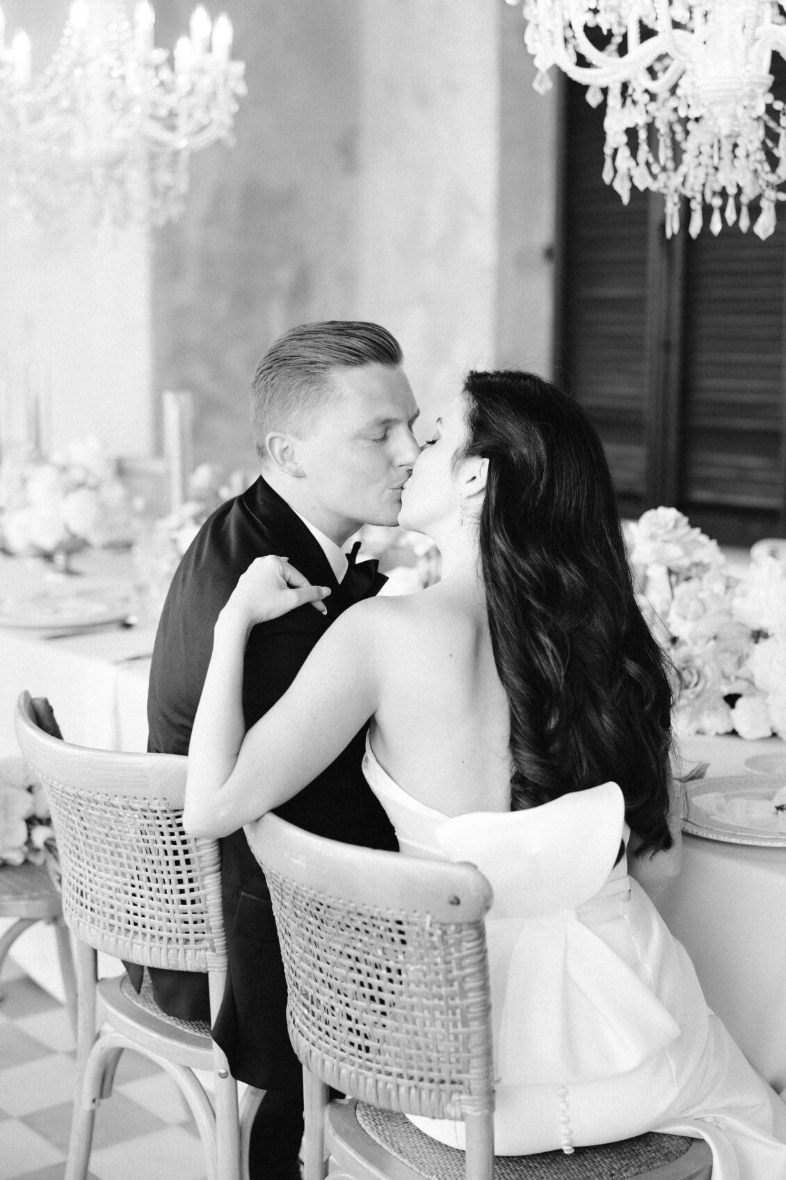 Black-and-white portrait of Jennifer and Travis kissing at dinner