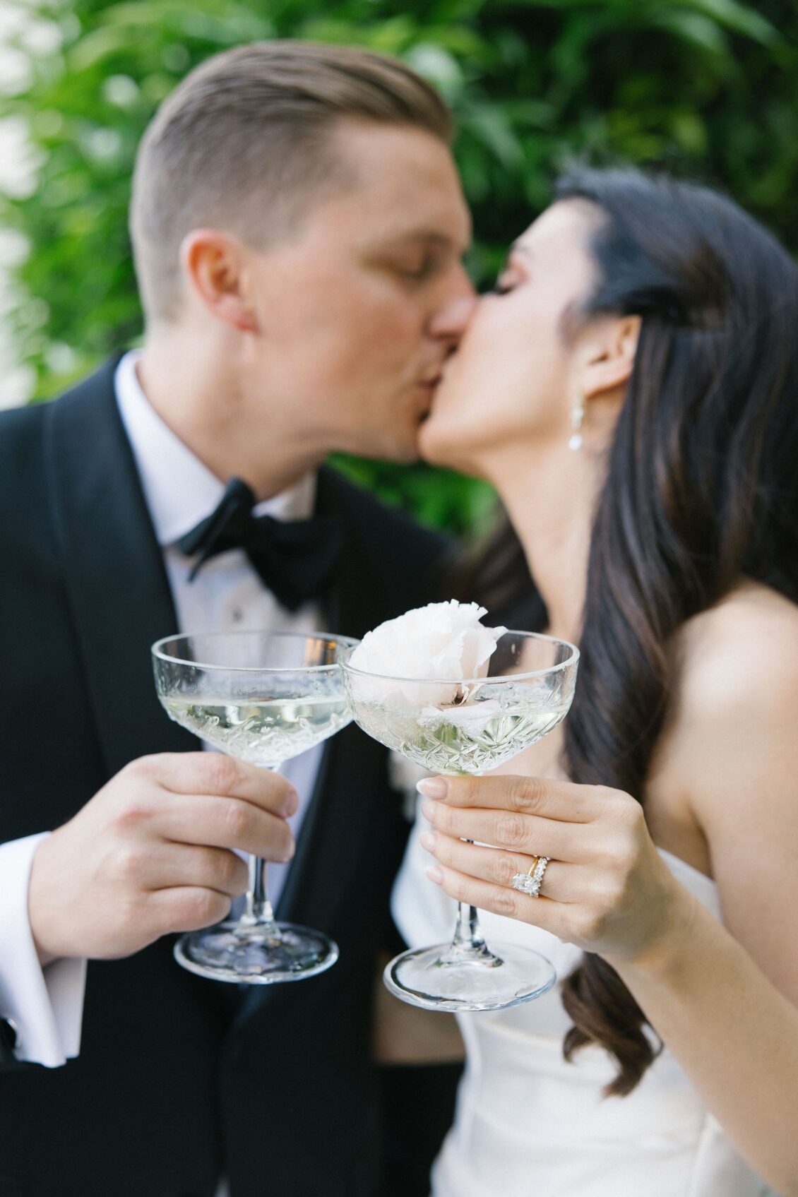 Newlyweds kissing over champagne coupes after the tower pour