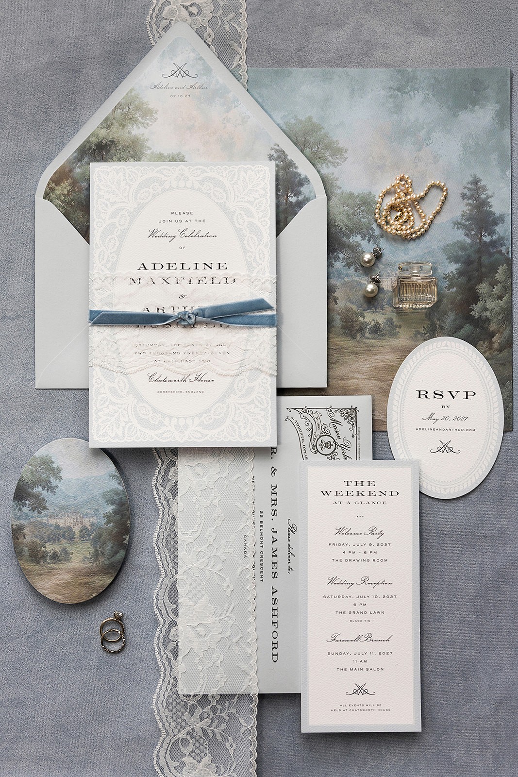 Wedding invitation suite arranged with blue ribbon, lace, reply card, envelope liner, and small gold details.
