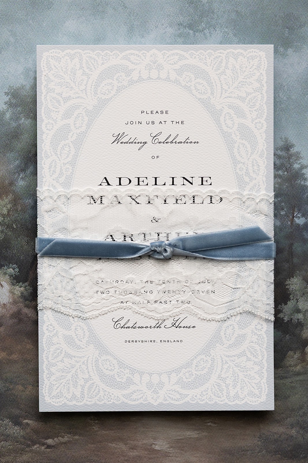 Embossed wedding invitation tied with a blue ribbon on a mottled blue background.