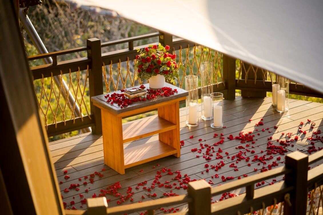 An outdoor wedding ceremony setting with red rose petals and an ocean view at Nekajui.