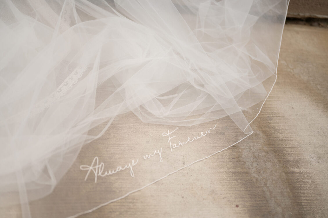 Layers of white veil spread across the pavement with Always and forever embroidered in cursive along the edge.