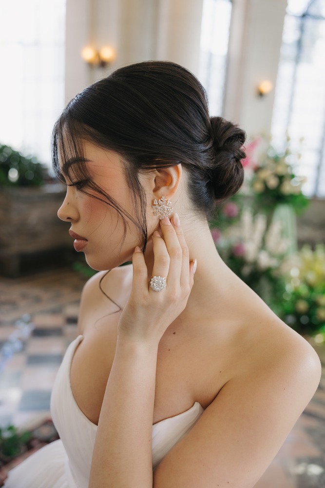 Bride adjusting her earring in profile