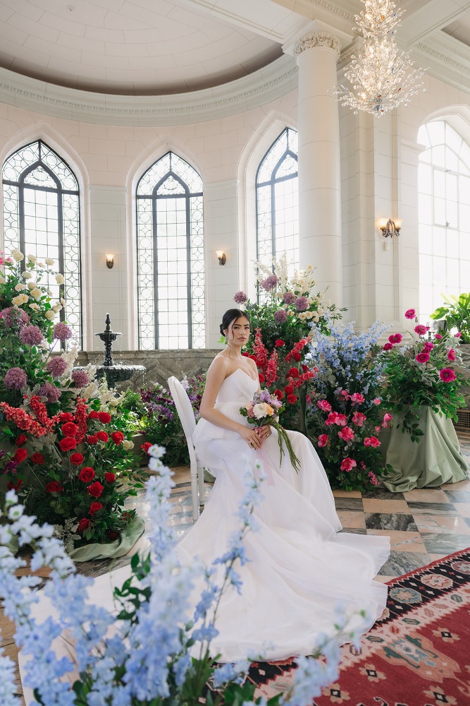 Bride in a white gown surrounded by layered botanicals