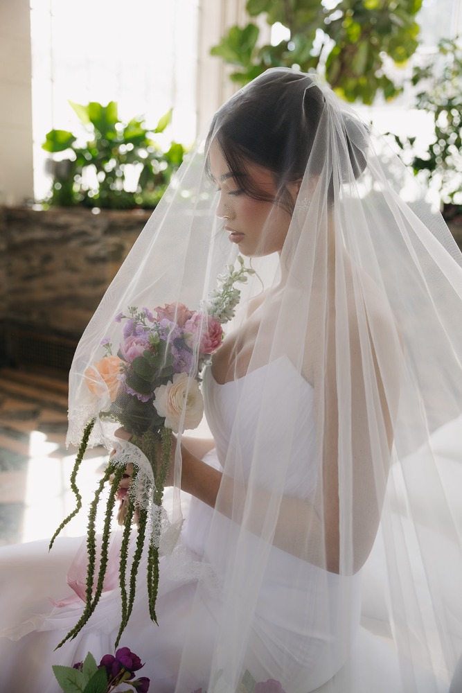 Veiled bridal profile holding a bouquet