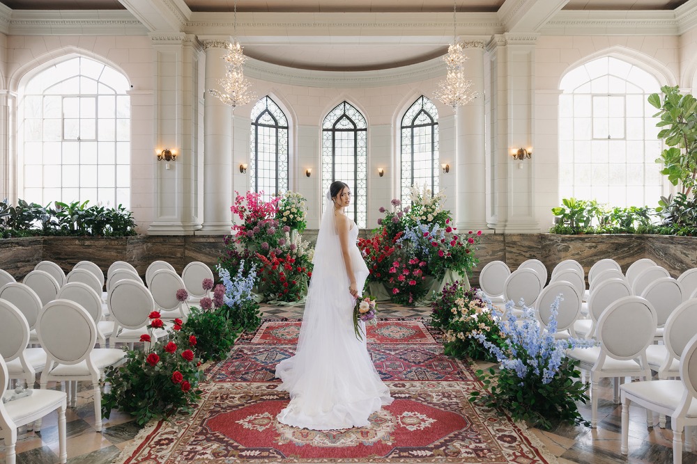 Wide ceremony-room view with floral aisle and white chairs