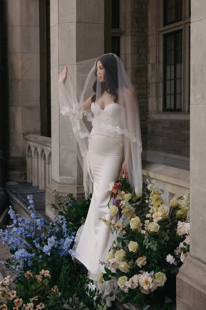 Bride lifting her veil beside Casa Loma’s stonework