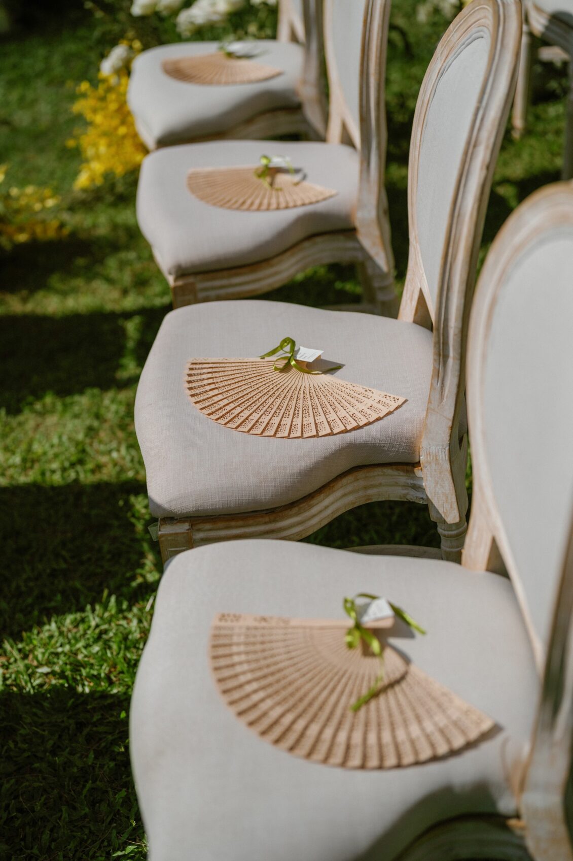 Christine and Shaun's Phuket wedding, fans placed on the chairs add a specific, guest-minded design detail.