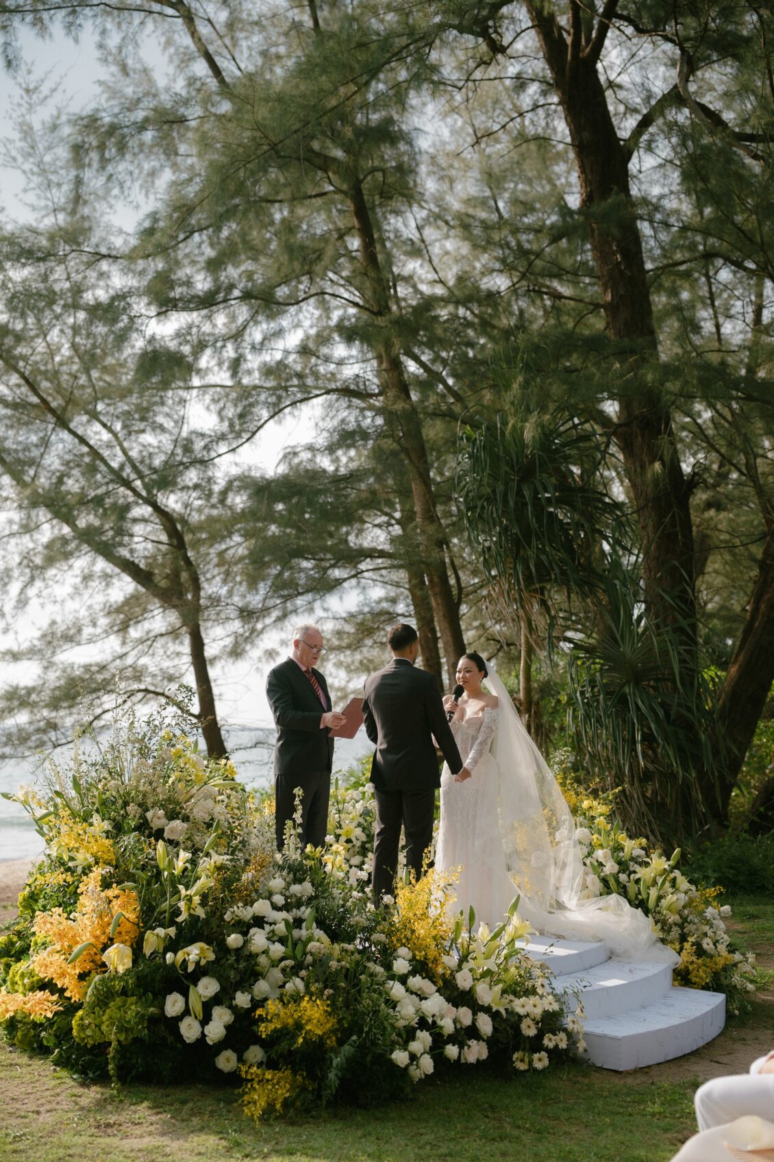Christine and Shaun's Phuket wedding, side view of couple and officiant establishes the exchange on the floral platform.