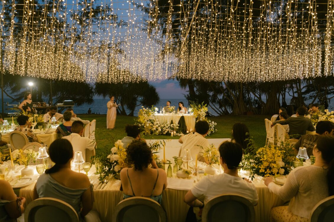 Christine and Shaun's Phuket wedding, dense fairy-light canopy and seated guests create the evening reception establishing frame.