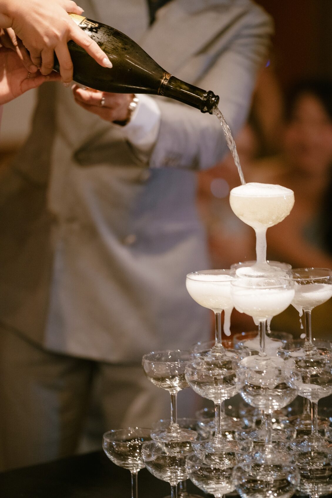 Christine and Shaun's Phuket wedding, champagne flowing into the coupe tower supplies a polished celebratory action detail.