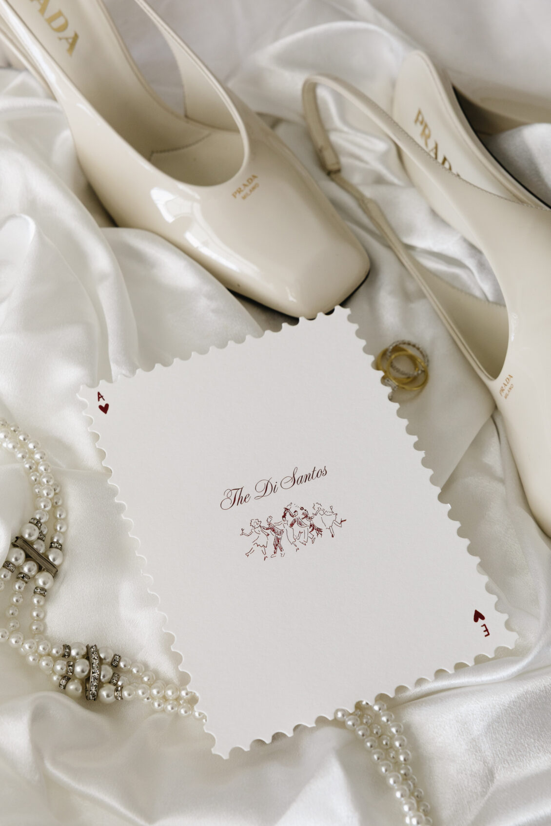 Wedding invitations, rings and keepsakes arranged with white flowers.