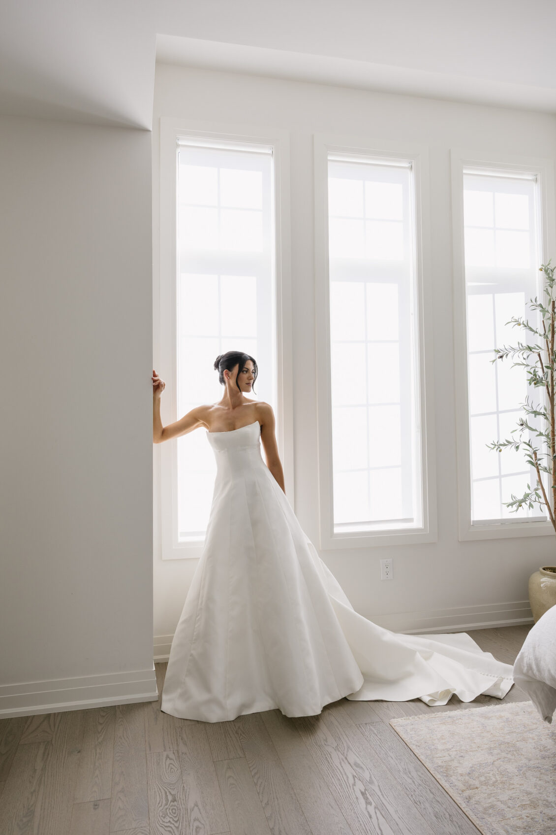 Erica poses by a window in her fitted wedding gown.