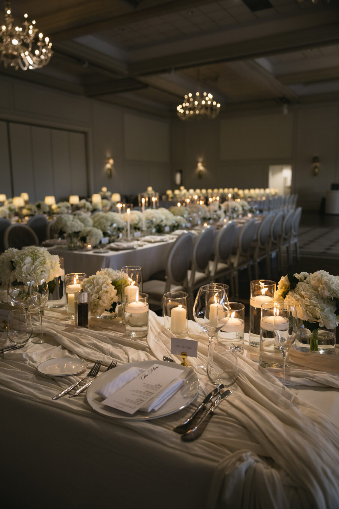 A reception table set with white flowers and sculptural lamps.