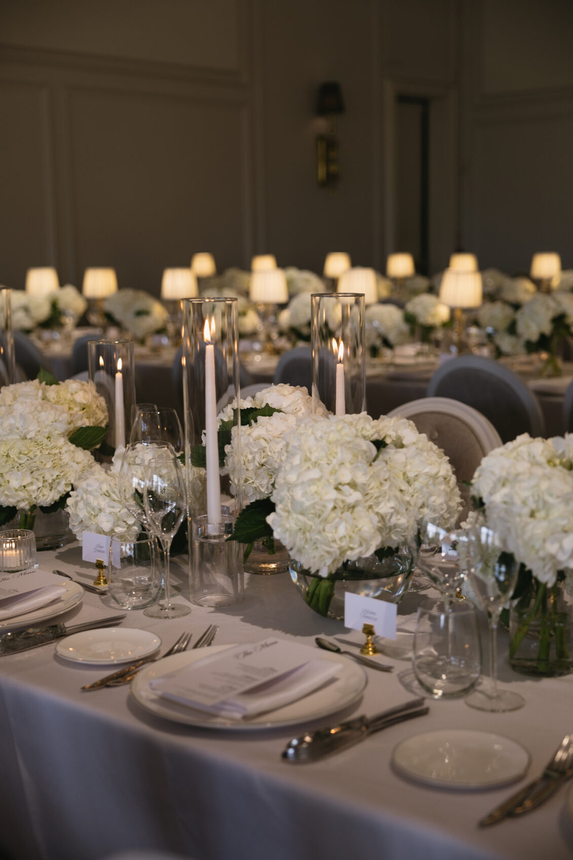 White flowers, glassware and candles on a reception table.