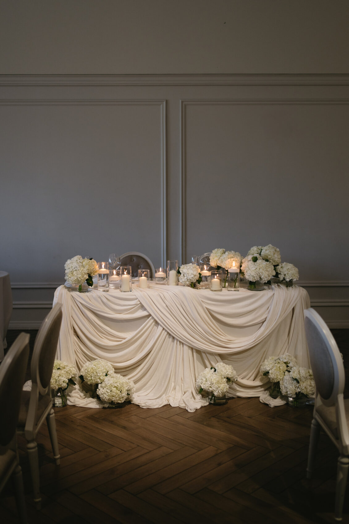 The couple’s table framed by white florals and warm lamps.