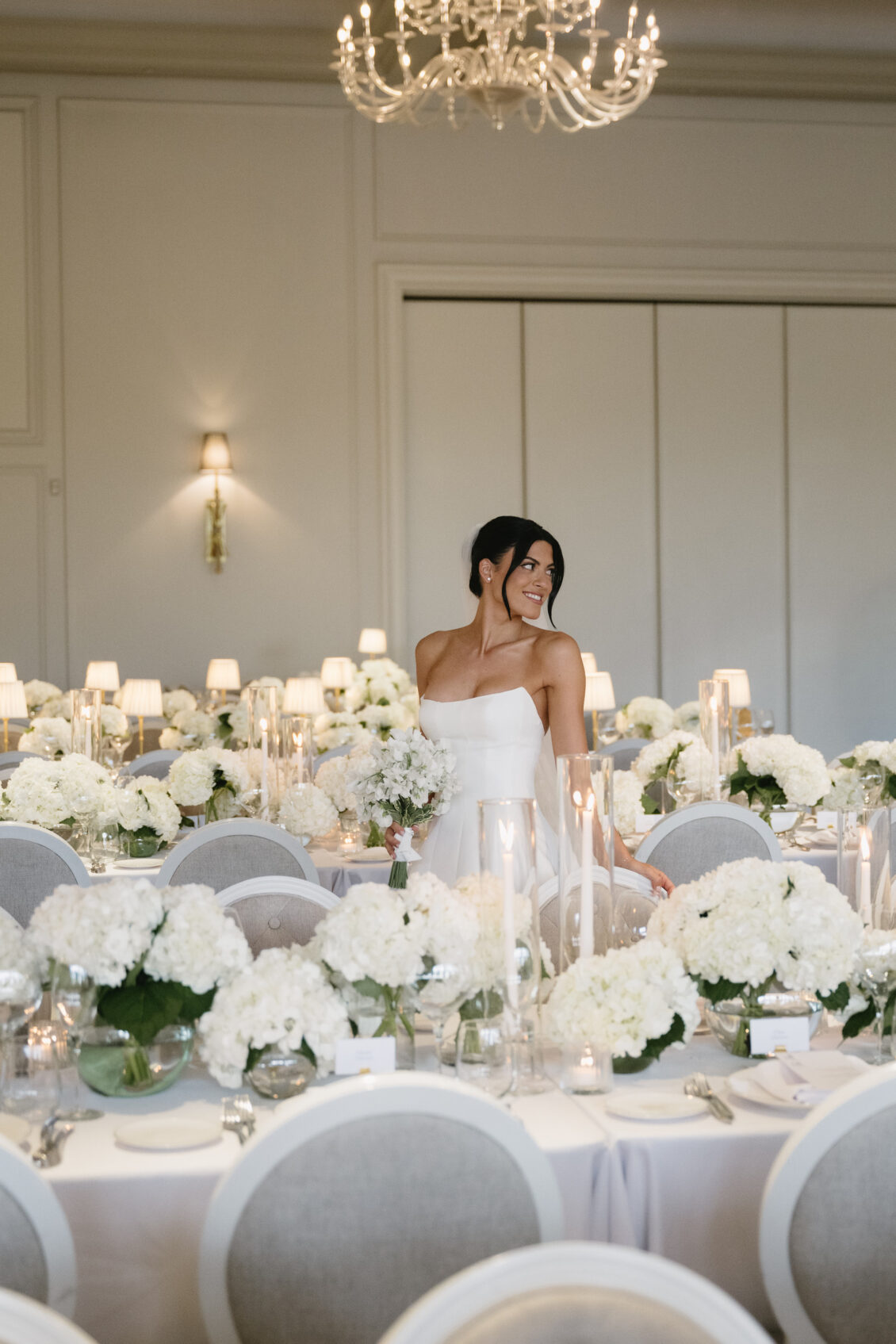 Erica poses among the reception tables and white florals.