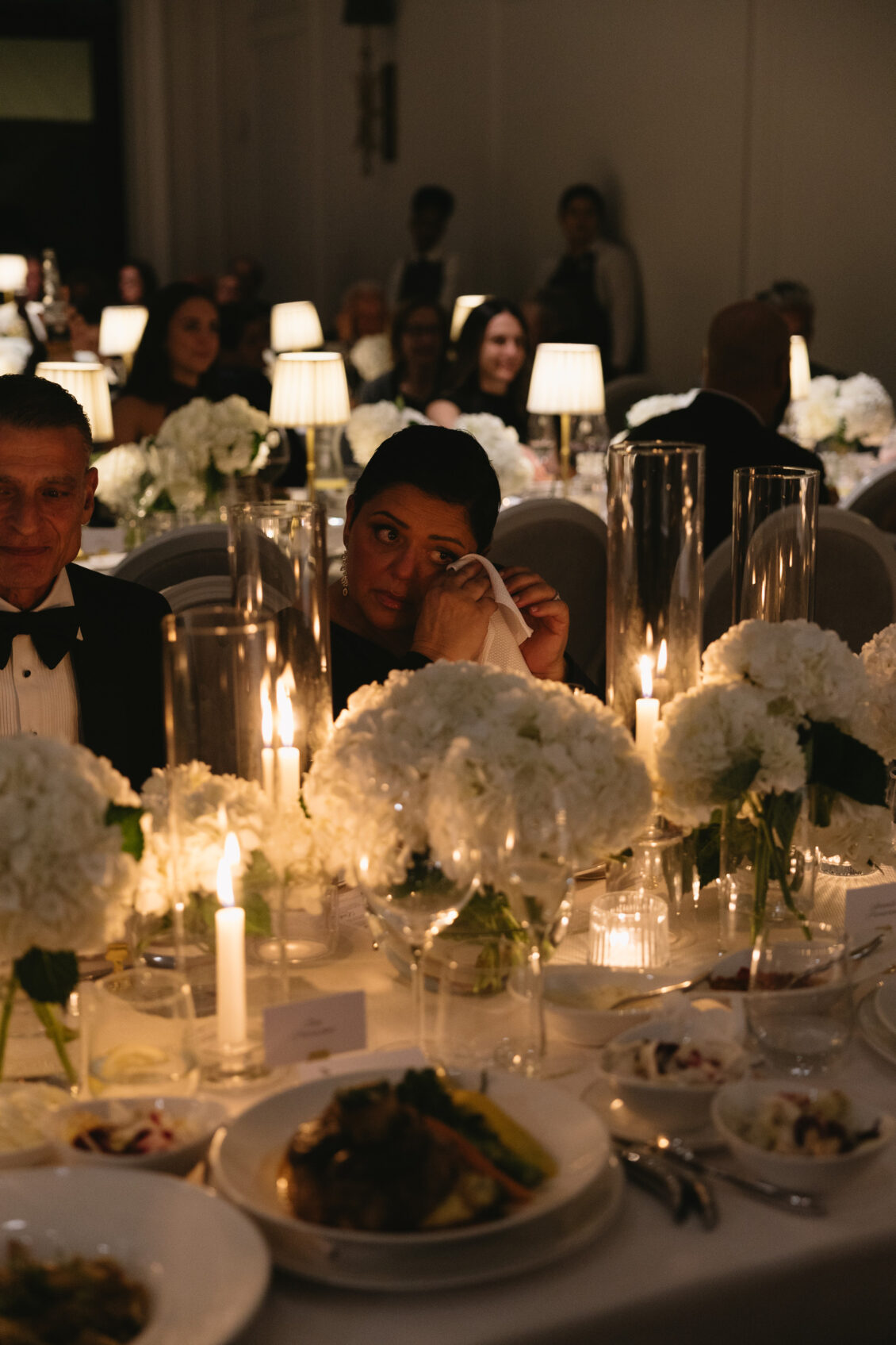 Wedding guests dine beneath warm table lamps.