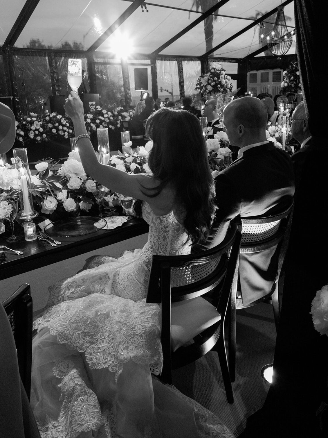Bride raising glass during seated toast.