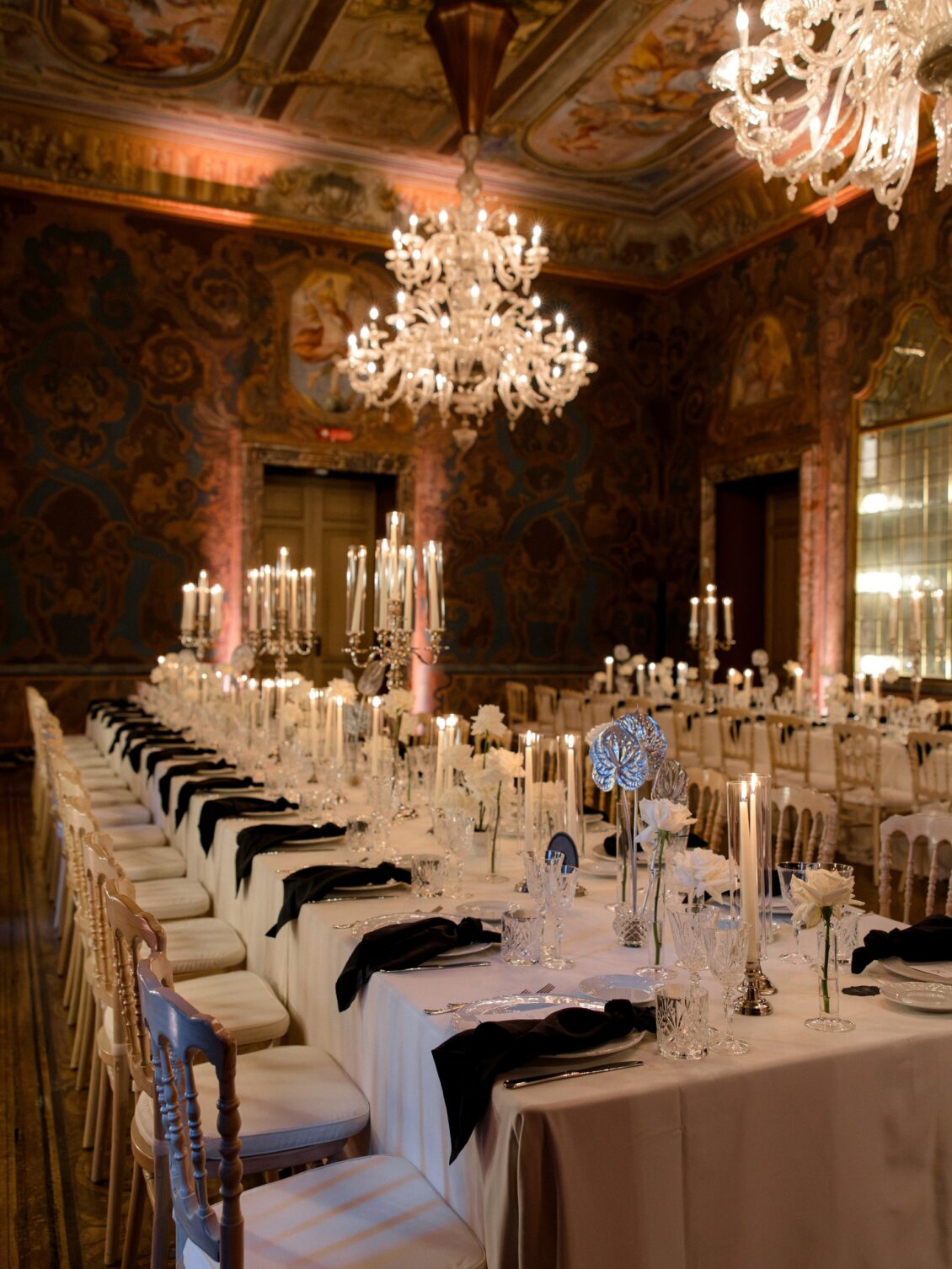 Candlelit reception tables beneath chandeliers at Villa Erba.