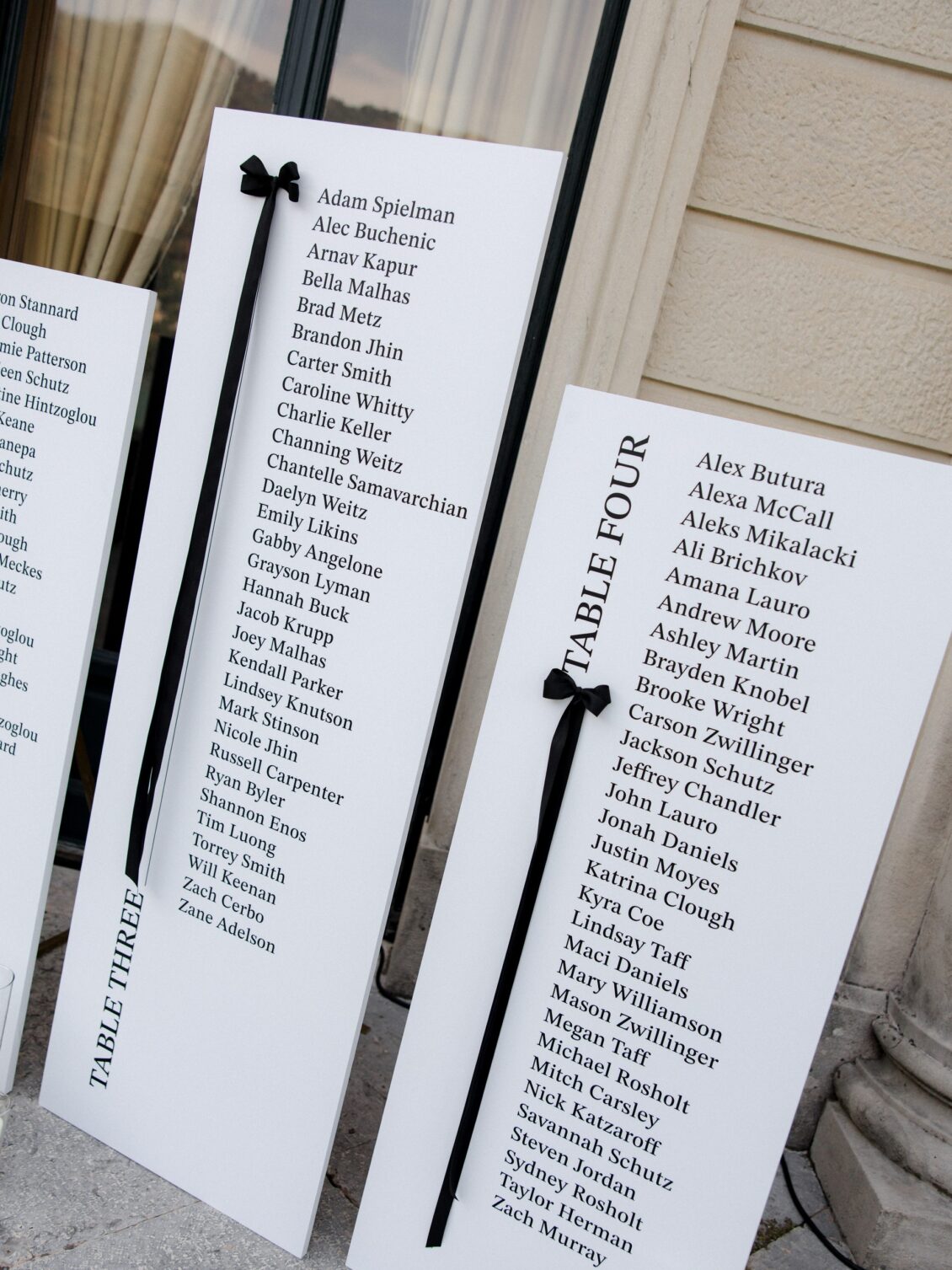 White wedding seating charts decorated with black ribbon bows.