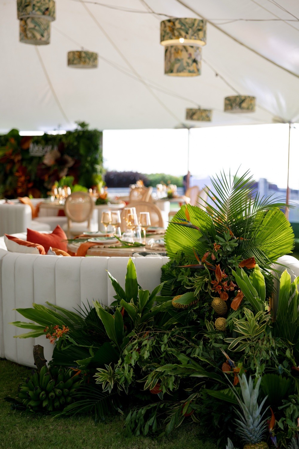 Tropical floral installation inside a white event tent at Nekajui