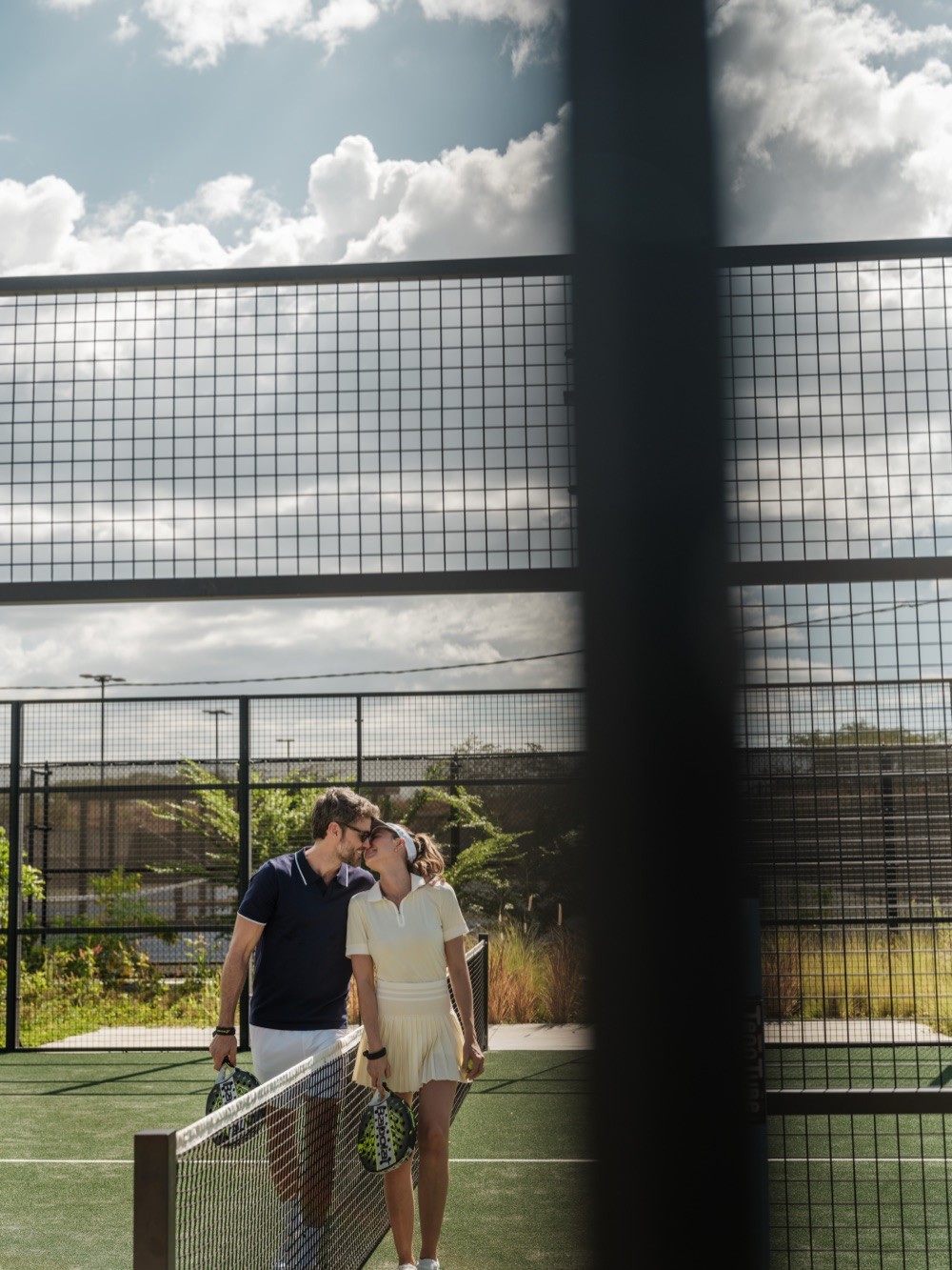 Couple sharing a kiss on the tennis court at Nekajui