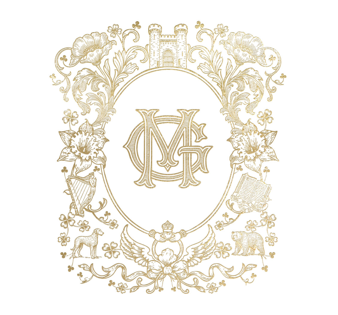 Ornate gold floral border with castle, harp, lion, bear, books, and a central overlapping “MG” monogram. Decorative and symmetrical design with intricate details on a white background, inspired by the elegance of an Irish castle wedding at Ashford Castle.