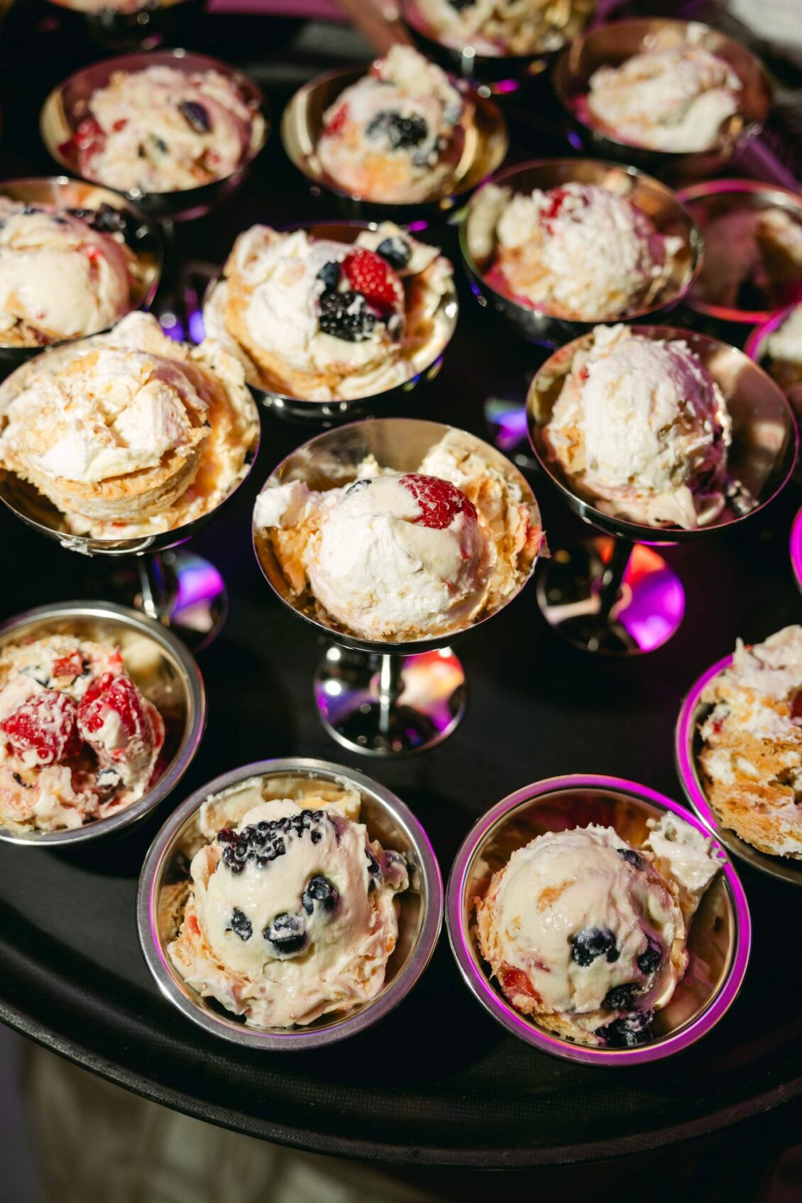 Servings of millefoglie cake topped with berries in vintage silver coupes