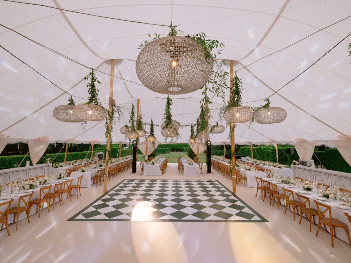 A crystal chandelier hangs above the green-and-white chequered dance floor at the heart of the white tent