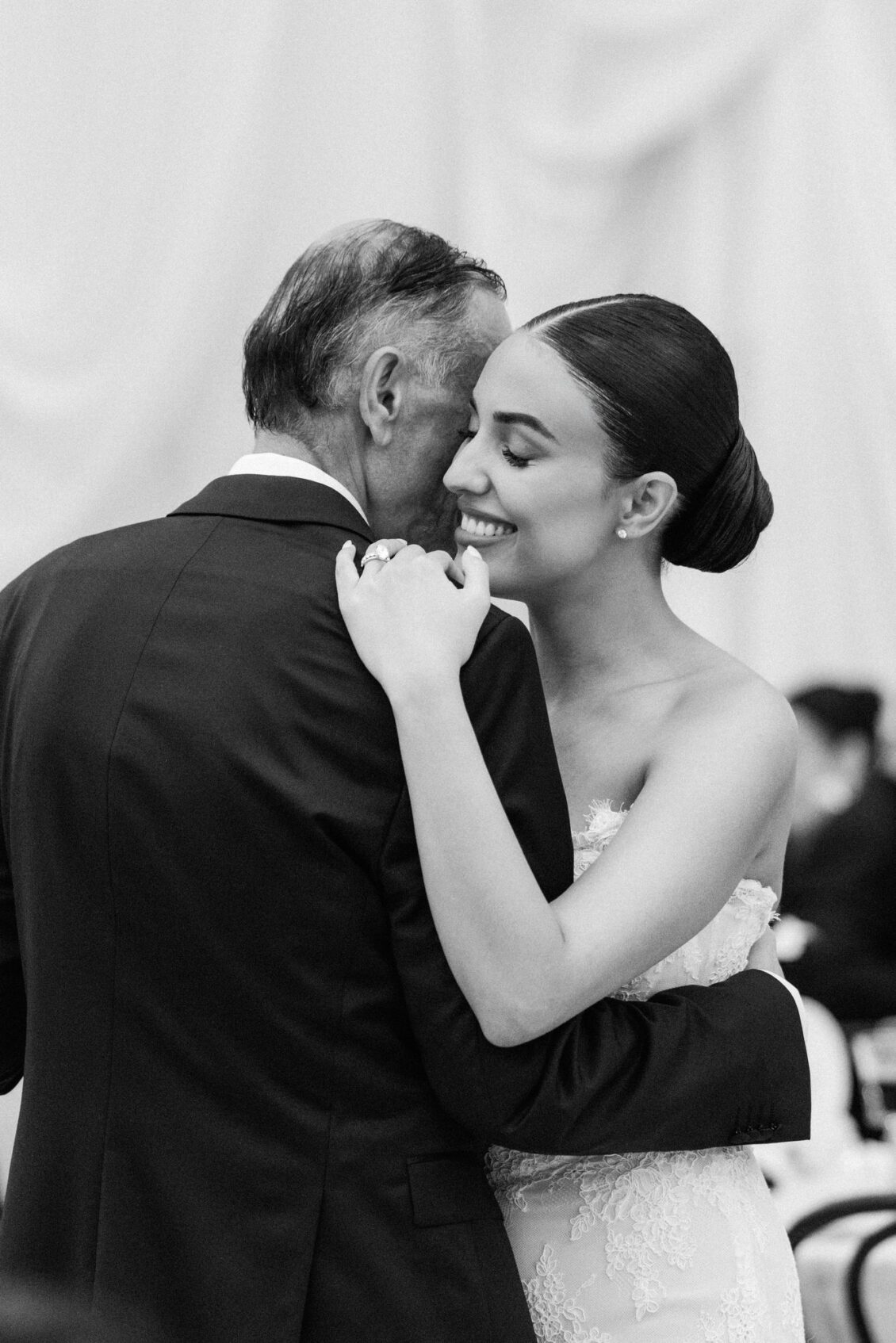 Black and white photo of Lara smiling as she dances with her father